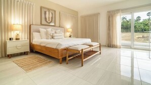 A spacious bedroom with a large bed, two bedside tables, a window with curtains, and a view of greenery outside. - Luxury 4BR Villa with Private Pool • 5 Min to Playa Dorada (Puerto Plata)