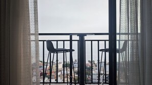 Ein Balkon mit zwei Stühlen und einem Tisch, mit Blick auf eine Stadtlandschaft.