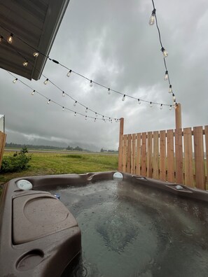 Ein Whirlpool mit Holzzaun und Lichterkette in einem Garten.