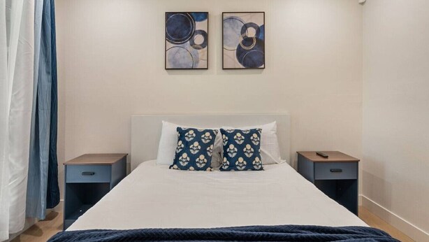 A bedroom with a bed, two nightstands, a headboard, and two abstract paintings on the wall. - Sunny Nest |Cowboy Pool & Bacyard| Newly Renovated (La Puente)