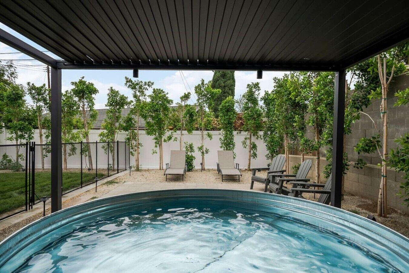 Piscina exterior techada con sillas de descanso y una pérgola.