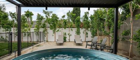 Piscina exterior techada con sillas de descanso y una pérgola.