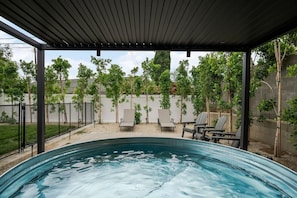 Ein überdachter Außenpool mit Liegestühlen und einer Pergola.