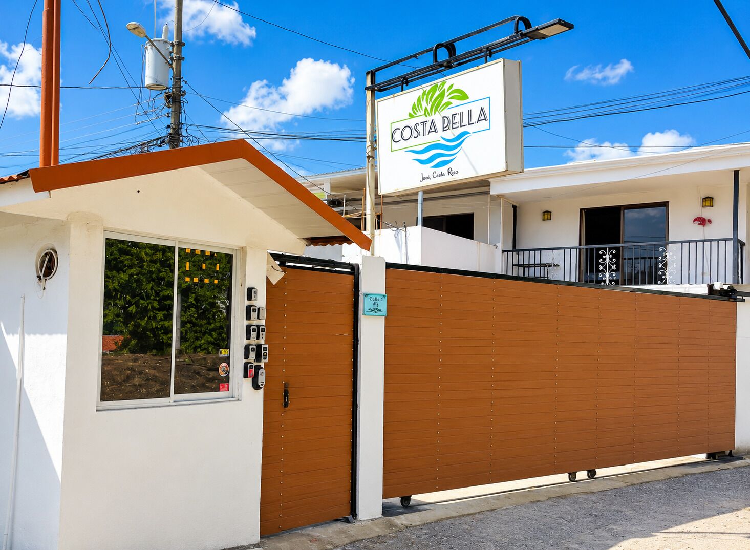 A Costa Bella hotel with a gated entrance, a signboard, and a balcony.