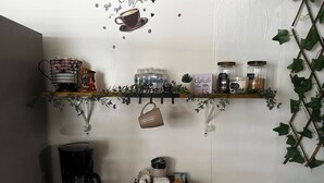 Un angolo caffetteria con una macchina da caffè, scaffali con articoli a tema caffè e un cartello che riporta la scritta 'COFFEE BAR'.