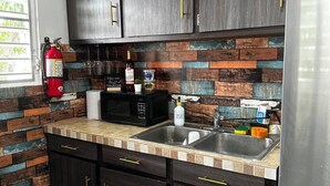 Una cucina con mobili scuri, un frigorifero in acciaio inossidabile, un forno a microonde e un lavello.