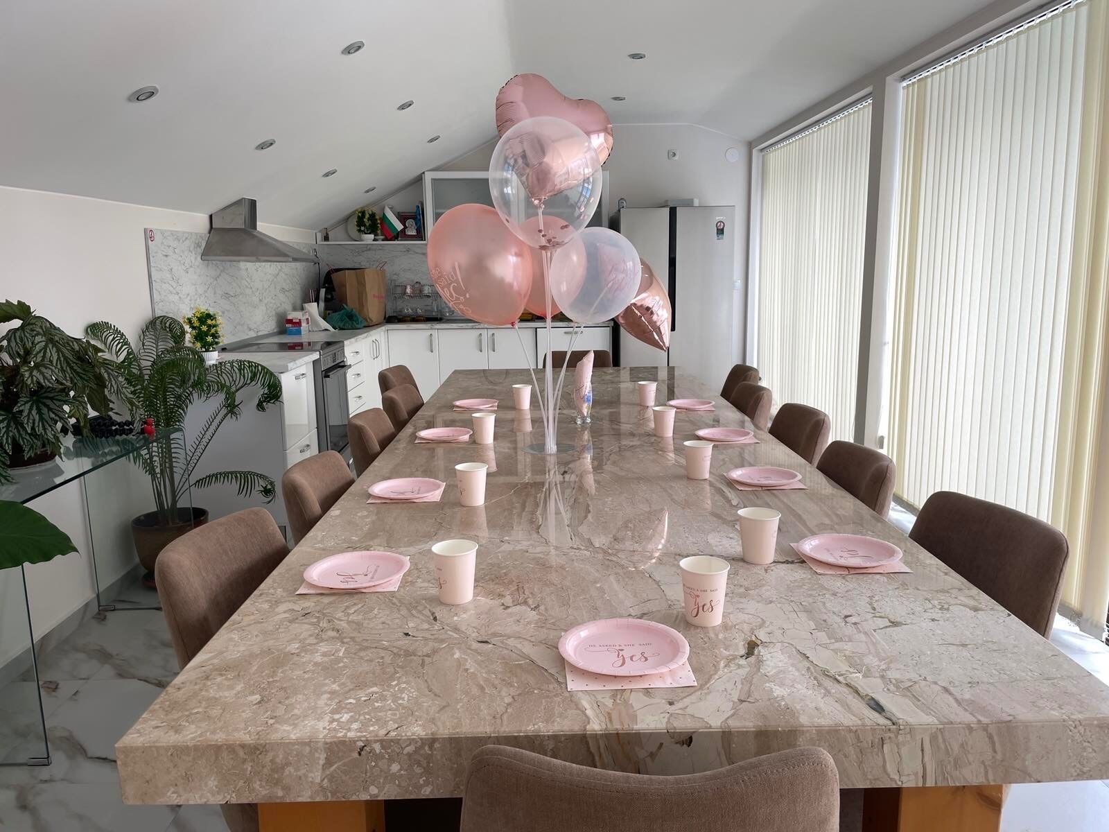 Un comedor moderno con una mesa de mármol dispuesta para una comida, rodeado de sillas.