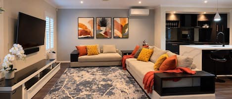 A modern living room with a sofa, a coffee table, and a flat-screen TV.