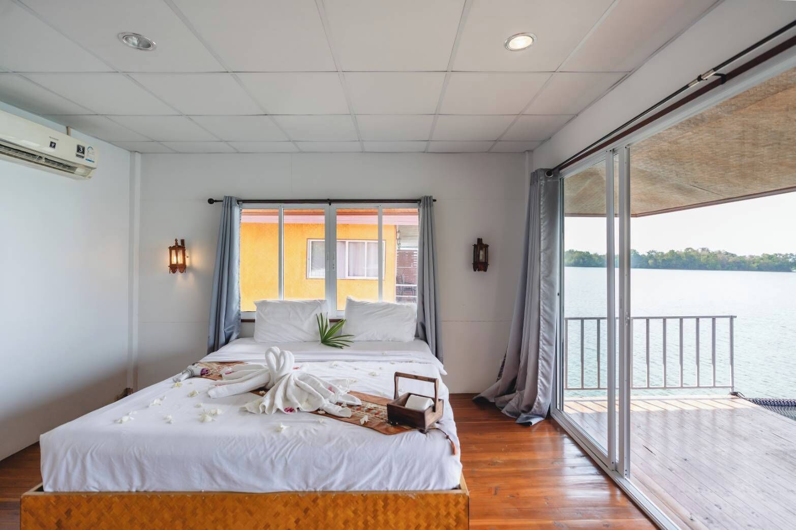 Un dormitorio con cama, ventana, vista al agua y balcón.