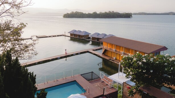 A resort with a swimming pool, overwater bungalows, and a wooden deck.