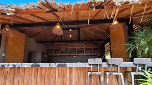 A bar area with a rustic wooden ceiling, hanging lights, and a bar counter with stools.