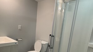 Un bagno con un water, uno spazio doccia, un lavandino e un tappeto a righe.
