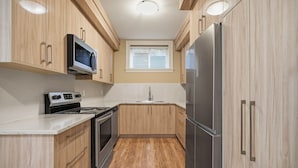 A modern kitchen with wooden cabinets, stainless steel appliances, and a window above the sink.