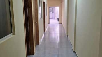 A long, narrow hallway with doors on one side and a plain wall on the other.