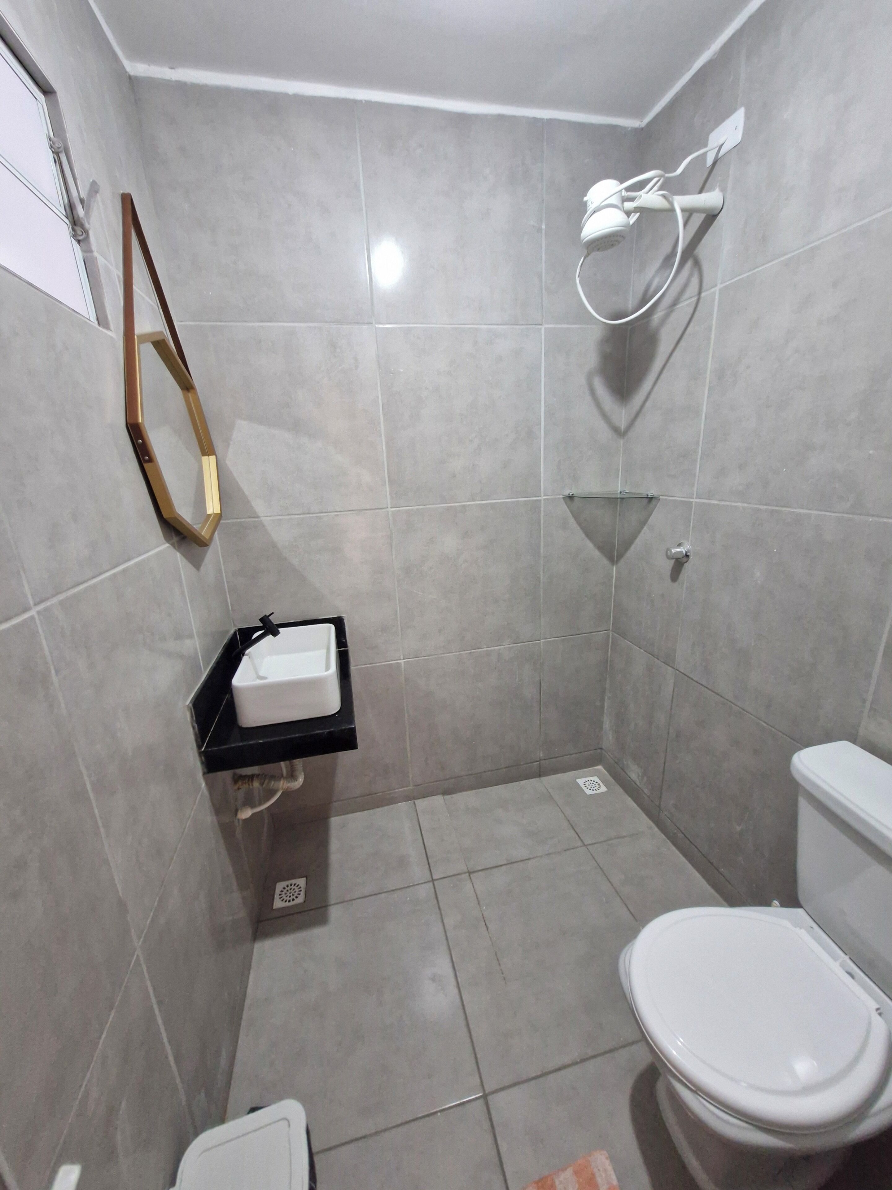 A small, modern bathroom with a toilet, a sink, and a shower area.