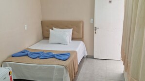 Ein Hotelzimmer mit Bett, Nachttisch, Tür und einer Lampe.