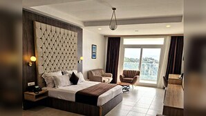 A modern hotel room with a large bed, a desk, a chair, and a view of the outdoors. - Hotel Cap Carbon (Béjaïa)