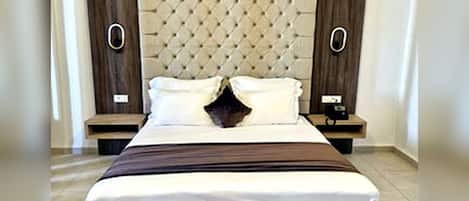 A bed with a tufted headboard, two bedside tables, and a nightstand with a lamp.