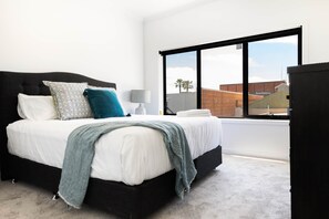 A bedroom with a large window, a bed with white bedding, and a black headboard. - The Lime Loft | Rooftop Views in Mildura's CBD (Mildura)