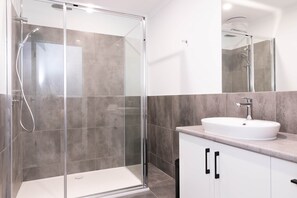 A modern bathroom with a glass-enclosed shower, a white sink, and a large mirror. - The Lime Loft | Rooftop Views in Mildura's CBD (Mildura)