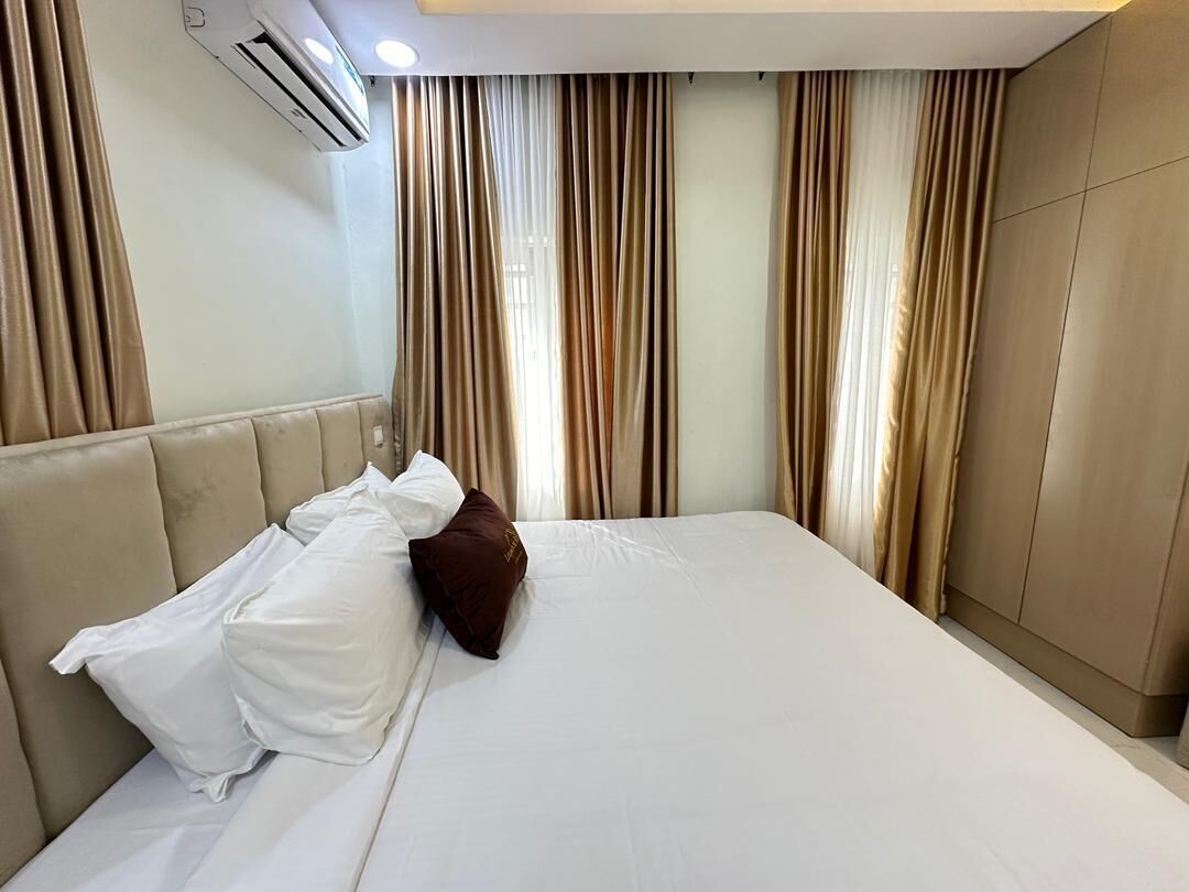 A hotel room with a bed, curtains, and an air conditioning unit.