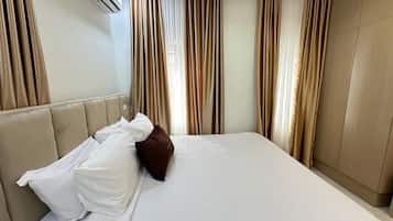 A hotel room with a bed, curtains, and an air conditioning unit.