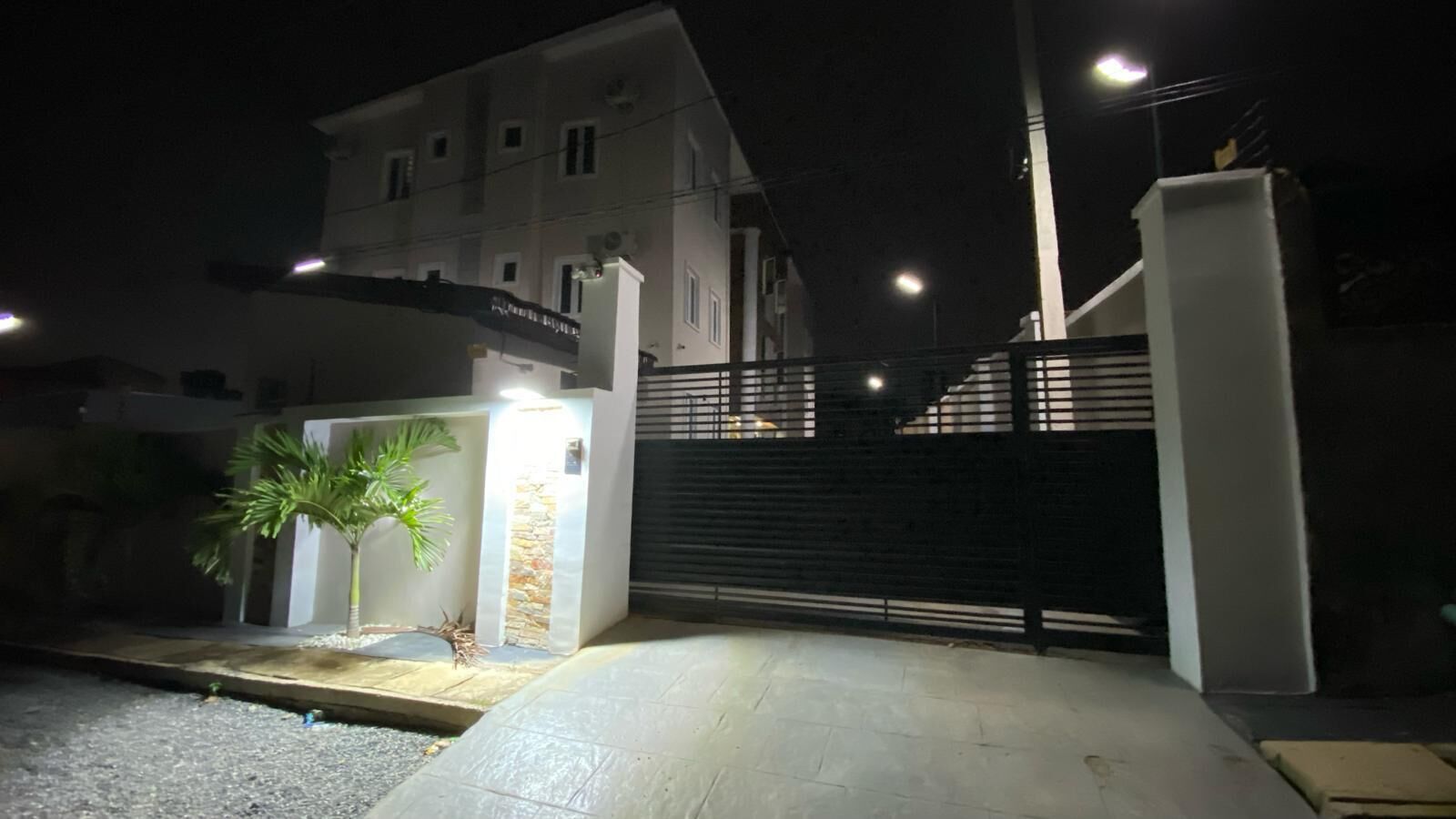 A gated entrance with a palm tree and a stone wall.