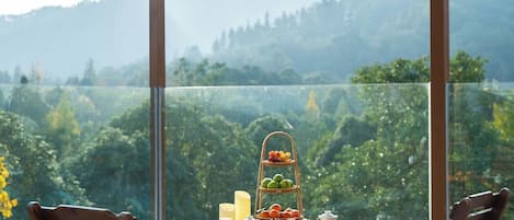 A balcony with a table set for two, overlooking a mountainous landscape.