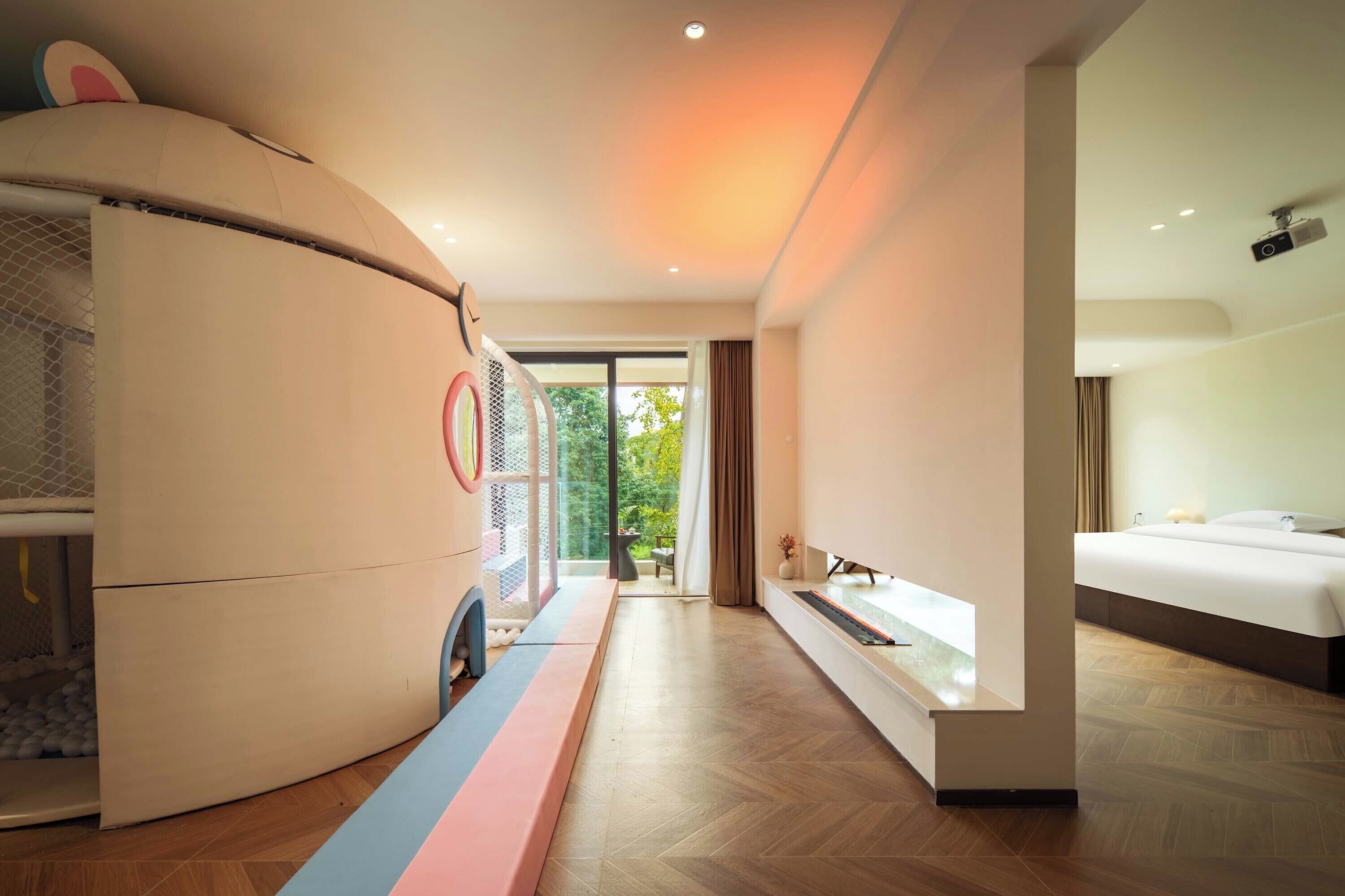 Una habitación de hotel moderna con una cama grande, armario empotrado, un pequeño rincón de descanso y vistas al exterior.