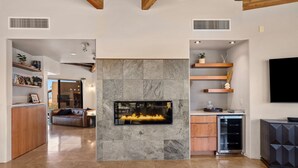 Una sala de estar moderna con chimenea, zona de cocina y espacio para sentarse.