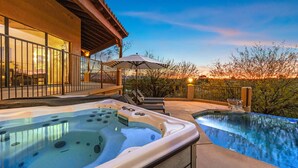 Un jacuzzi y una piscina con zona de patio, un área de estar cubierta y vistas al atardecer.