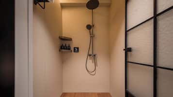 A shower with a handheld showerhead, a wall-mounted faucet, and a shelf with toiletries.