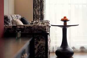 A living room with a patterned sofa, a small round table with a fruit bowl, and a vase. - YEMEI Art Villas (Beihai)