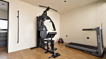 A gym with a weight machine, a treadmill, and dumbbells.