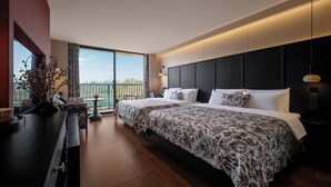 Quarto de hotel moderno com uma cama grande, uma escrivaninha, vista para o exterior e uma varanda.
