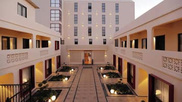 A hotel courtyard with a central entrance, multiple balconies, and decorative lighting.