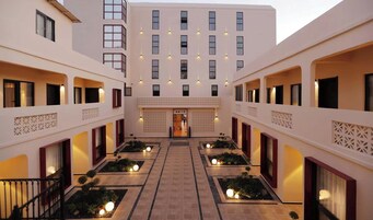 Pátio de hotel com entrada central, várias varandas e iluminação decorativa.