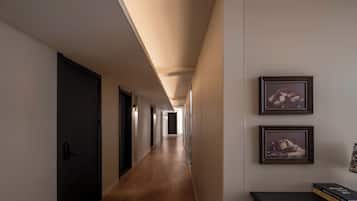 A hallway with wooden flooring, dark doors, and framed artwork on the walls.