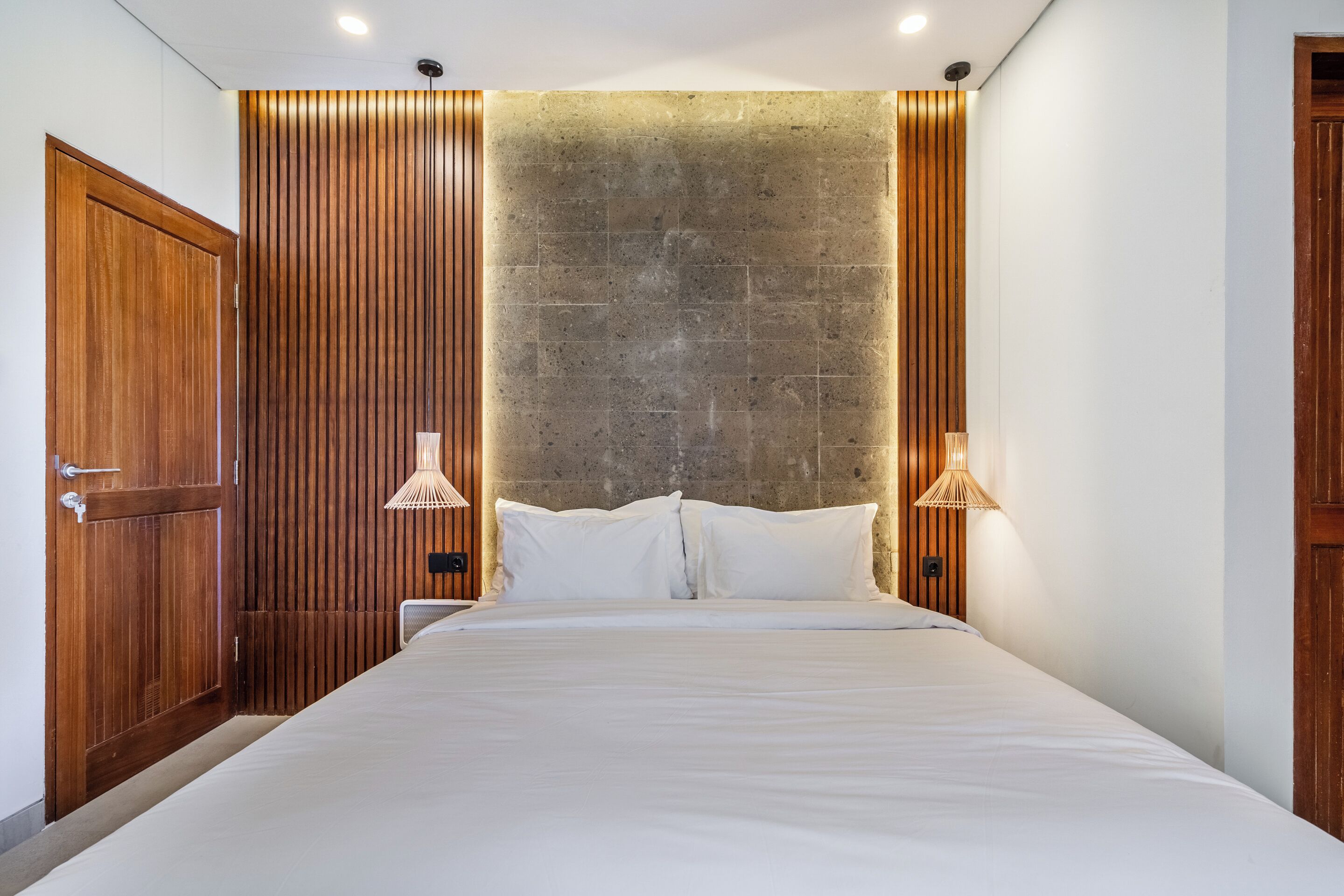 A bedroom with a large bed, wooden panel walls, and two bedside lamps.