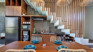 A modern kitchen with a central island, built-in appliances, and a dining area with wicker chairs. - Bhiseka Villa Kedungu by Aishwarya Bali (Tabanan)