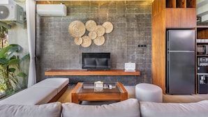 A modern living room with a flat-screen TV, a wooden coffee table, and a built-in wooden cabinet. - Bhiseka Villa Kedungu by Aishwarya Bali (Tabanan)