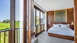 A bedroom with a large bed, a view of a green field, and a balcony with a railing. - Bhiseka Villa Kedungu by Aishwarya Bali (Tabanan)