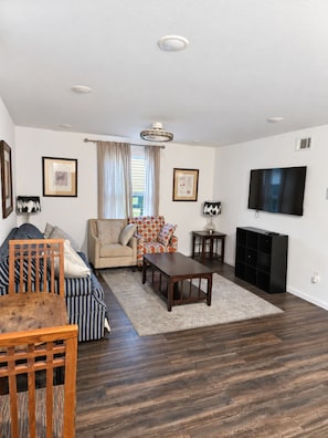 A living room with a sofa, armchair, coffee table, and a TV. - Spacious 2BR/2BA Home in EaDo Houston – Full Kitchen, W/D, Near Downtown (Houston)