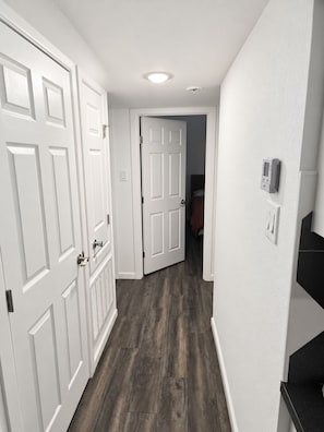 A hallway with white doors and a dark wooden floor. - Spacious 2BR/2BA Home in EaDo Houston – Full Kitchen, W/D, Near Downtown (Houston)