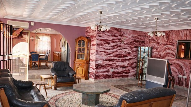 Un salon comprenant un canapé, des fauteuils, une table basse, un téléviseur et un mur décoré de motifs.