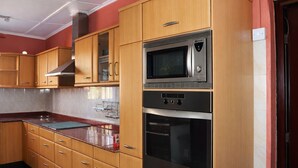 Une cuisine avec des meubles en bois, un four à micro-ondes, un four traditionnel et une hotte aspirante.
