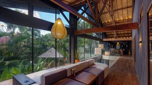 Een modern interieur met een zithoek, grote ramen en uitzicht op groen.