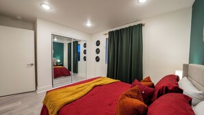 Una camera da letto con un letto grande, uno specchio, un armadio e una finestra con tende.