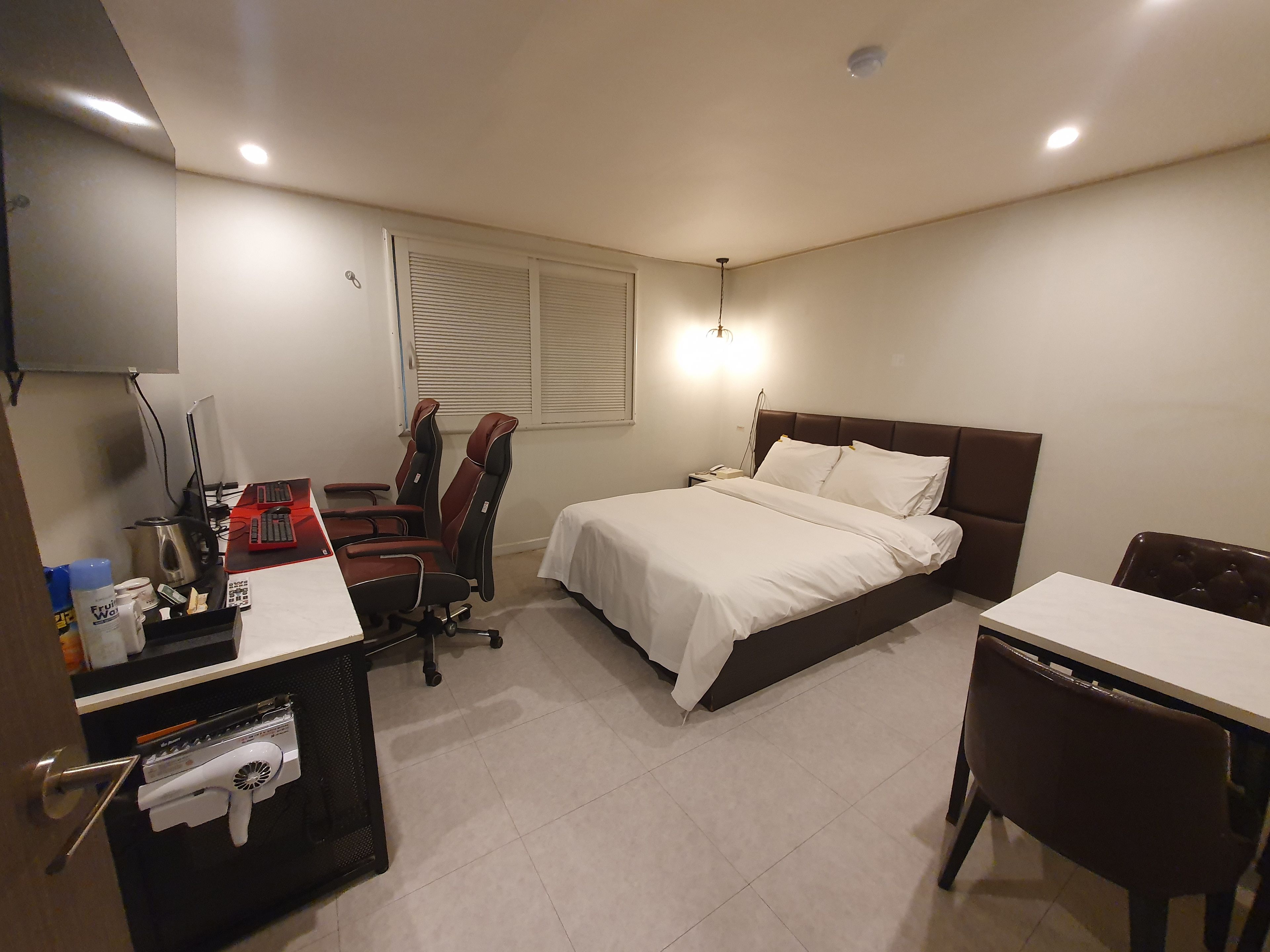 Ein Hotelzimmer mit Bett, Schreibtisch, Stuhl und einer kleinen Küchenzeile.
