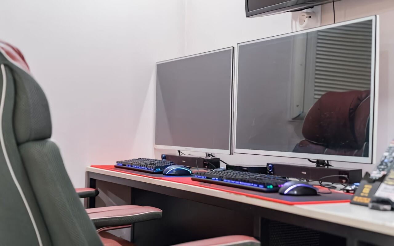 A computer desk with two monitors, a keyboard, a mouse, and a chair.